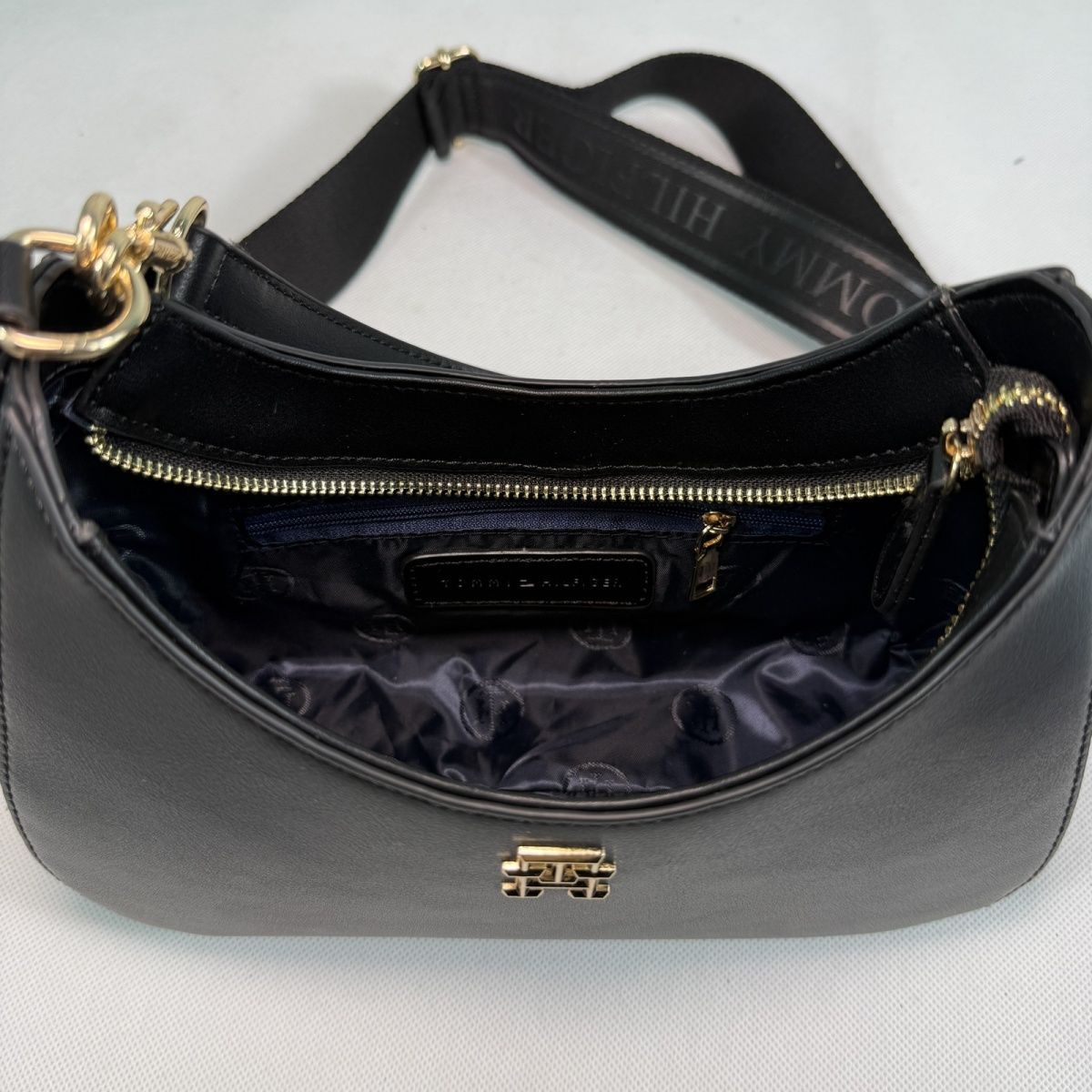 Tommy Hilfiger – TH მონოგრამითა და ნახევრადმთვარისებური ფორმით გაფორმებული ტრენდული ჩანთა thumbnail