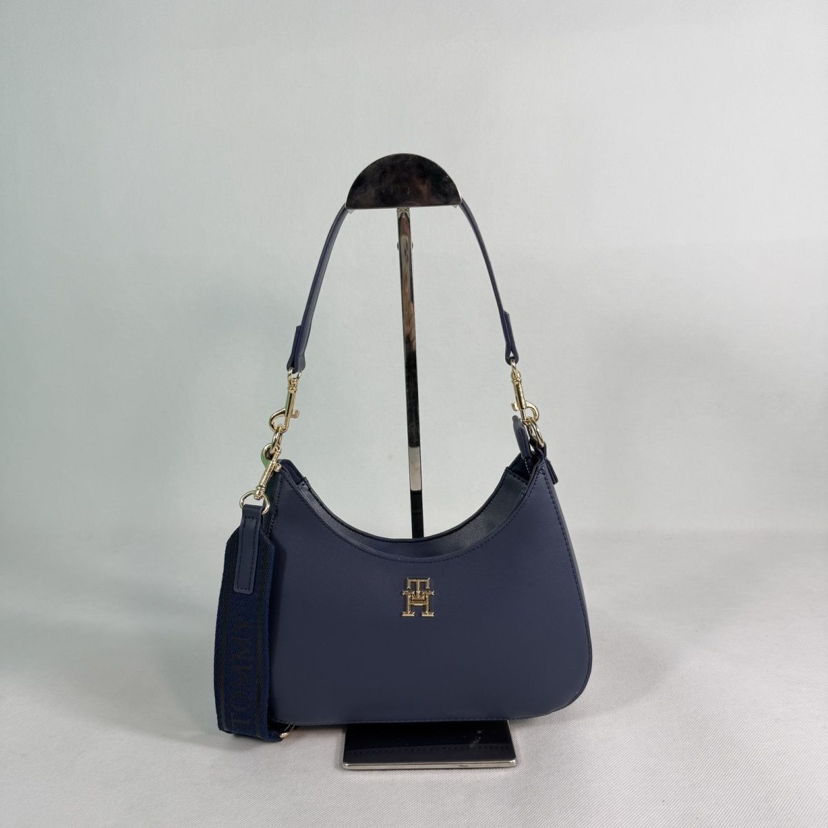 Tommy Hilfiger – TH მონოგრამითა და ნახევრადმთვარისებური ფორმით გაფორმებული ტრენდული ჩანთა